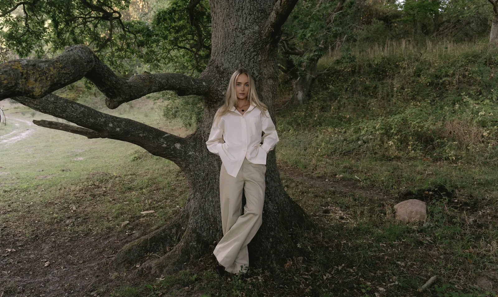 Sacha standing against an old oak tree at the edge of a field